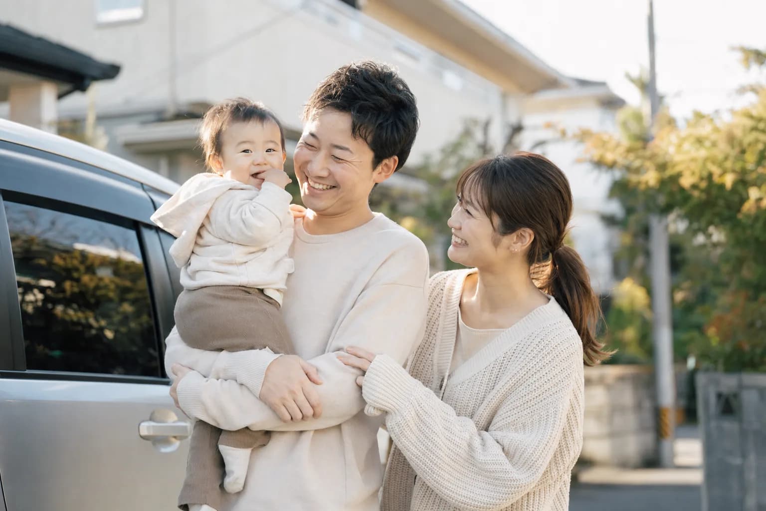 30代の夫婦と赤ちゃんの家族が車のそばに立つ様子