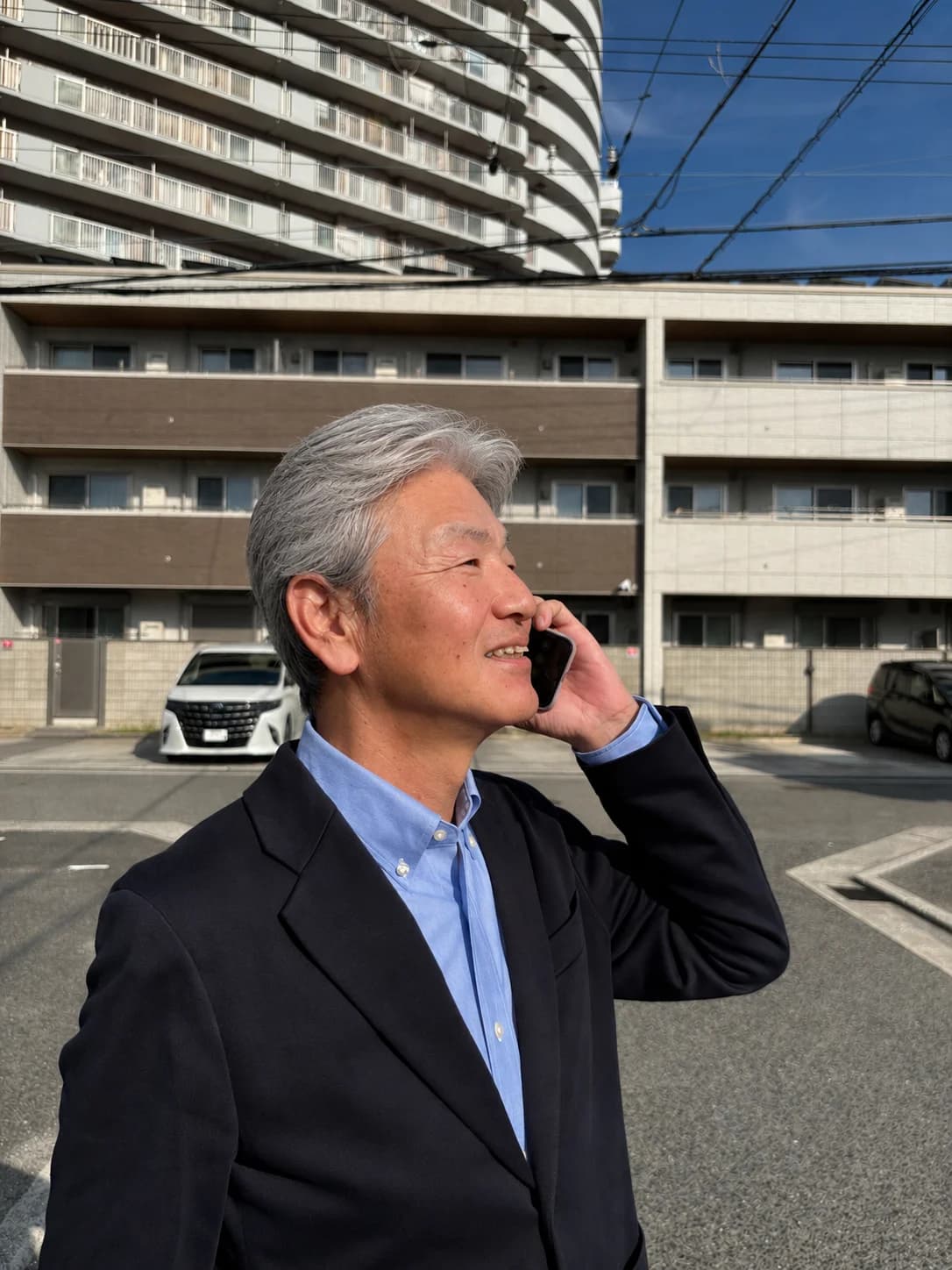 スーツ姿でお客様と電話でお話しする代表 尾木達也